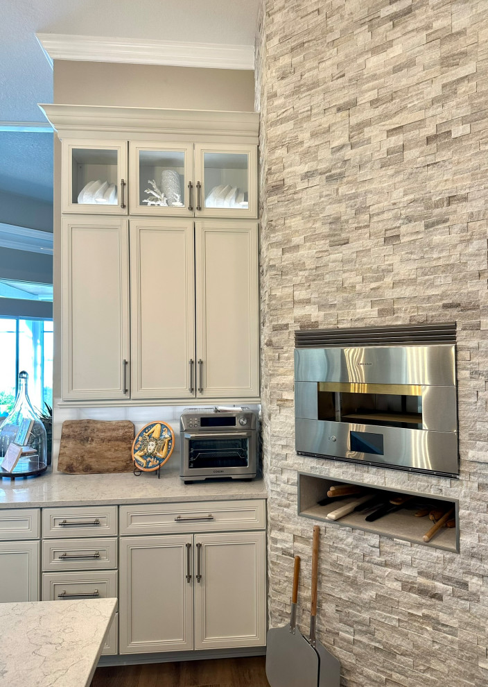 Inspiration for a transitional kitchen remodel in Orlando with recessed-panel cabinets, white cabinets, quartz countertops, white backsplash, porcelain backsplash, stainless steel appliances and white countertops
