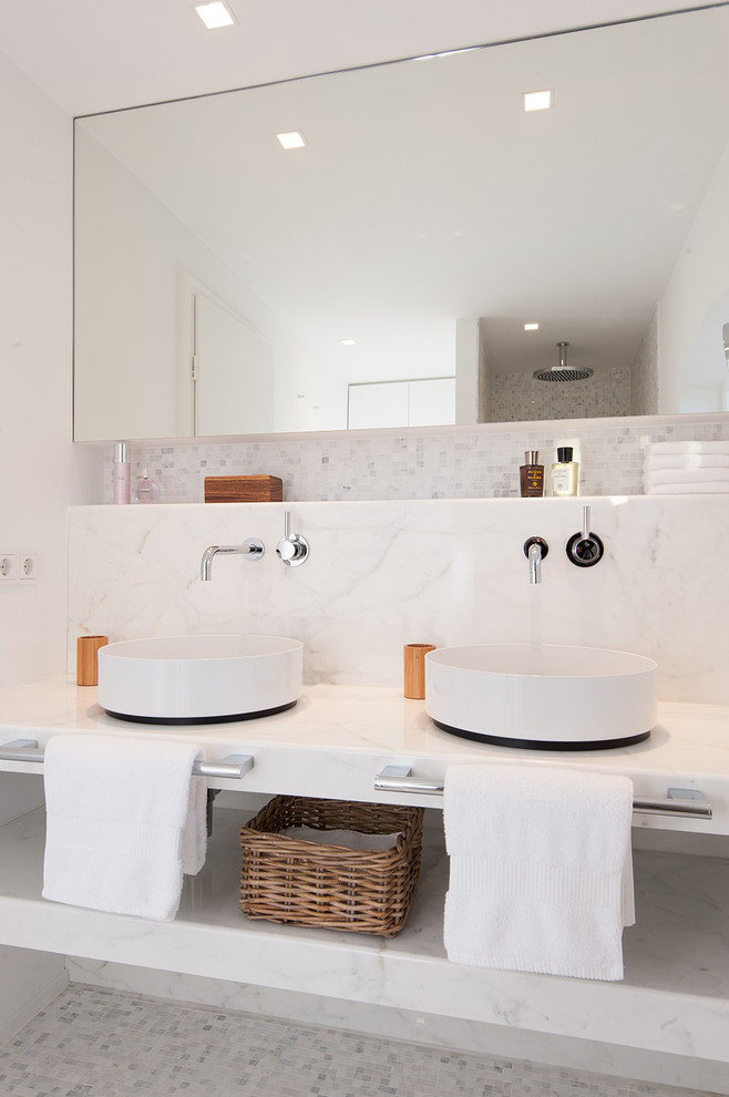 This is an example of a mid-sized contemporary bathroom in Other with a vessel sink, open cabinets, white cabinets, stone tile, white walls, mosaic tile floors, marble benchtops, white tile and white benchtops.