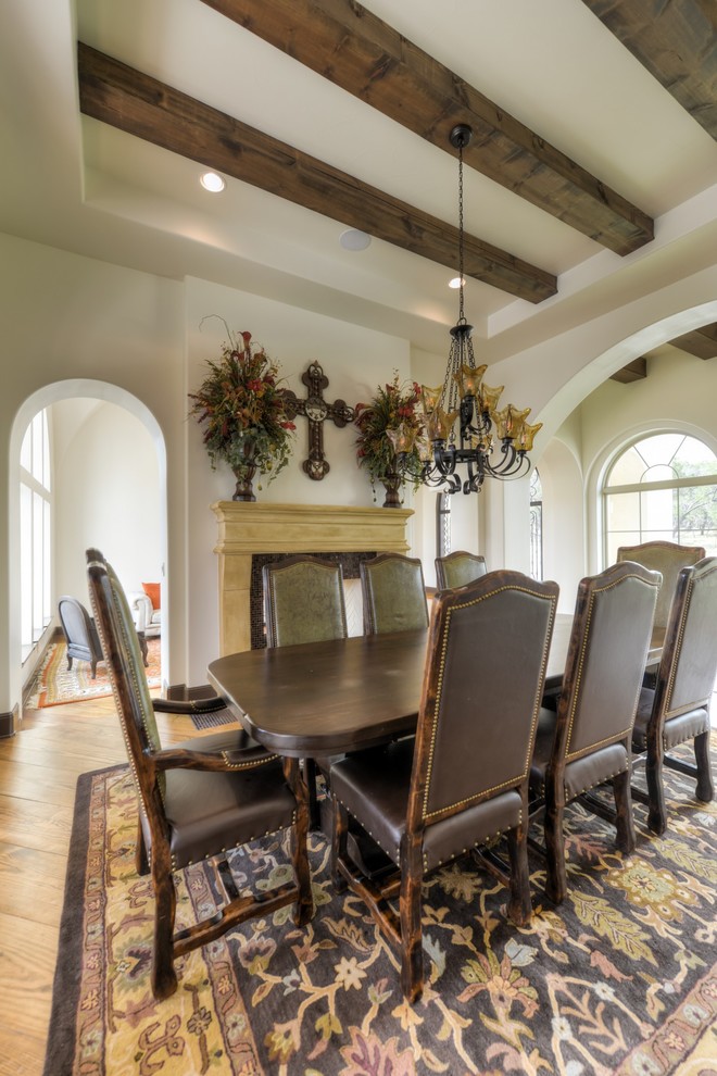 Large mediterranean separate dining room in Austin with white walls, medium hardwood floors and a two-sided fireplace.