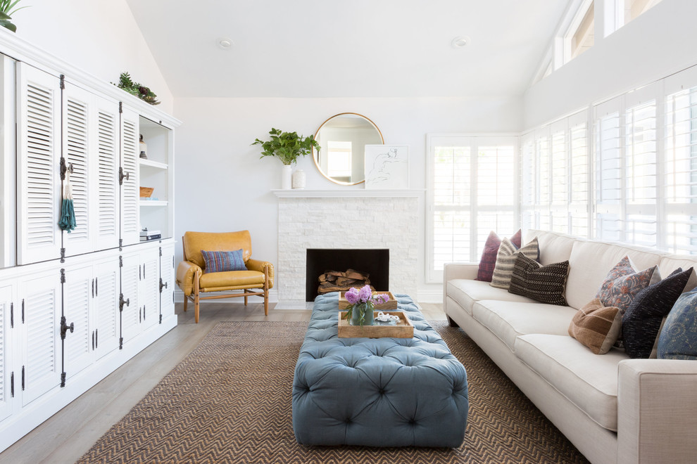 This is an example of a beach style family room in Los Angeles with white walls, no fireplace and a concealed tv.