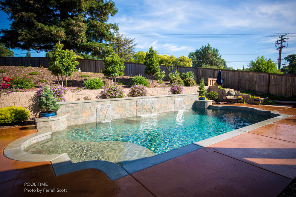 Inspiration for a mid-sized traditional backyard rectangular pool in Sacramento with a water feature and decking.