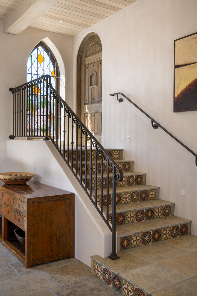 This is an example of a small mediterranean tile straight staircase in Santa Barbara with tile risers and metal railing.