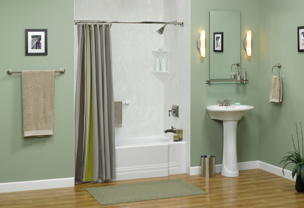 This is an example of a mid-sized transitional bathroom in Austin with an alcove tub, a shower/bathtub combo, gray tile, porcelain tile, green walls, light hardwood floors, a pedestal sink, brown floor and a shower curtain.