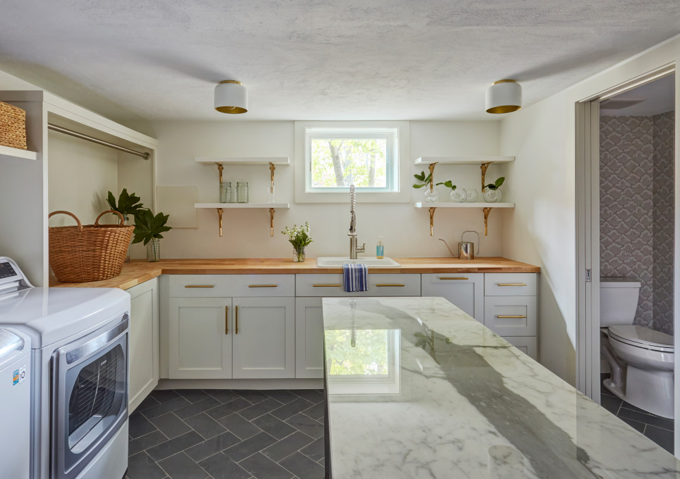 This is an example of a large country l-shaped laundry room in Other with a drop-in sink, shaker cabinets, white cabinets, white walls, slate floors, a side-by-side washer and dryer and grey floor.