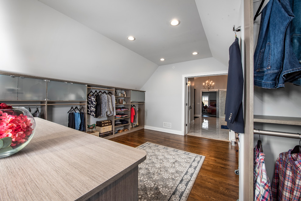 Photo of a large transitional gender-neutral walk-in wardrobe in Chicago with shaker cabinets, grey cabinets, medium hardwood floors and brown floor.