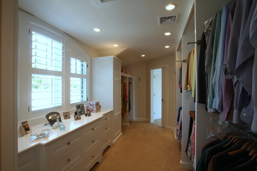 Design ideas for a large transitional gender-neutral walk-in wardrobe in Orange County with recessed-panel cabinets, white cabinets and carpet.