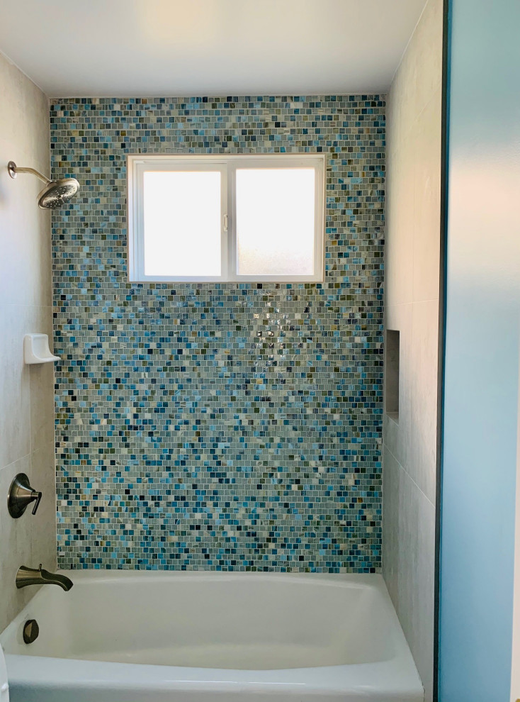 Inredning av ett modernt mellanstort badrum, med ett platsbyggt badkar, en dusch/badkar-kombination, en toalettstol med separat cisternkåpa, grå kakel, glasskiva, blå väggar, klinkergolv i porslin, ett piedestal handfat, grått golv och dusch med duschdraperi