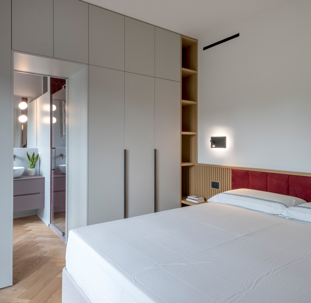 This is an example of a medium sized contemporary master bedroom in Milan with red walls, medium hardwood flooring and wood walls.