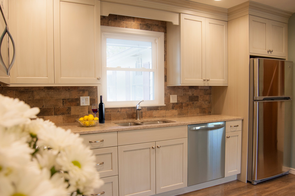 Mid-sized transitional l-shaped vinyl floor eat-in kitchen photo in Chicago with an undermount sink, recessed-panel cabinets, beige cabinets, quartz countertops, brown backsplash, porcelain backsplash, stainless steel appliances and no island