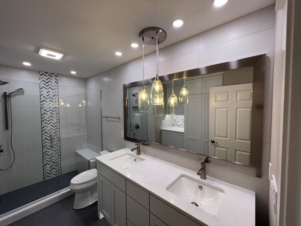 Inspiration for a mid-sized bathroom in Other with shaker cabinets, white cabinets, a one-piece toilet, white tile, porcelain tile, porcelain floors, an undermount sink, engineered quartz benchtops, grey floor, a hinged shower door, white benchtops, a shower seat, a double vanity and a freestanding vanity.