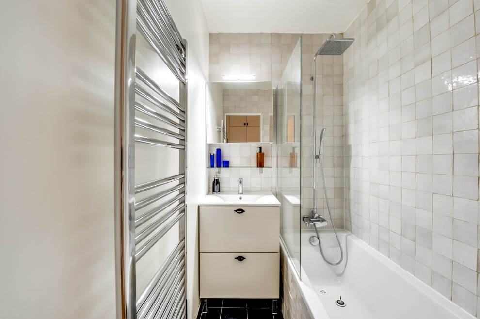This is an example of a small transitional kids bathroom in Paris with flat-panel cabinets, beige cabinets, an undermount tub, a shower/bathtub combo, beige tile, mosaic tile, cement tiles, a console sink, limestone benchtops, black floor, an open shower and white benchtops.