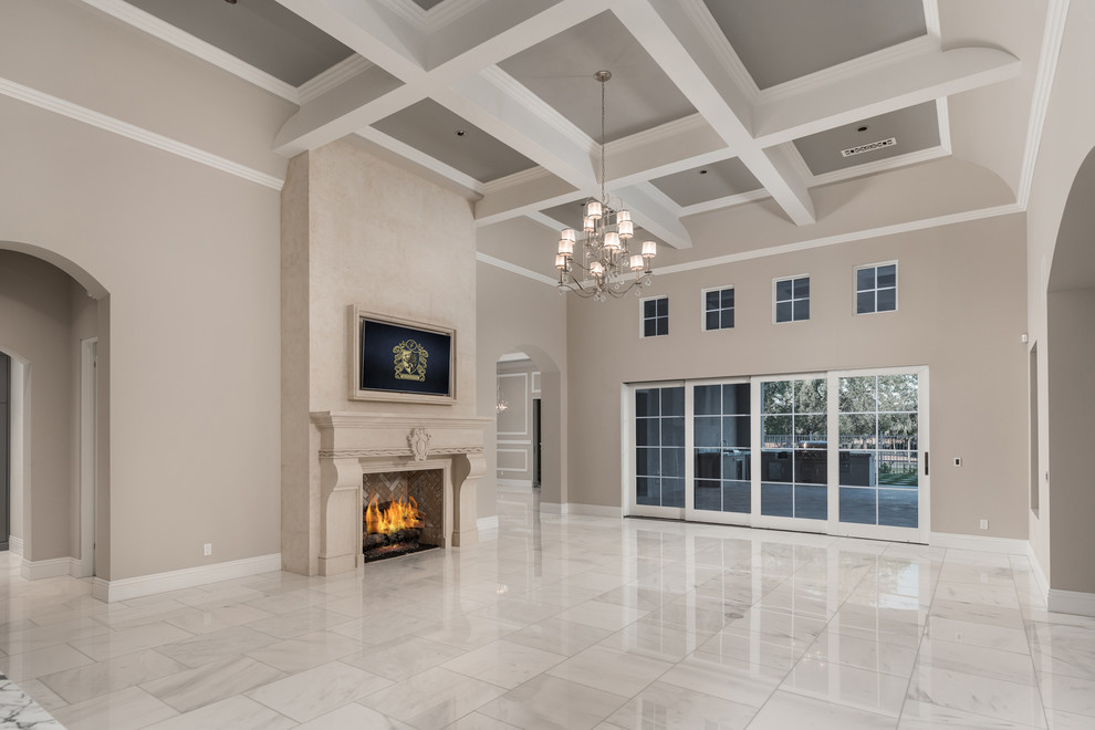 This is an example of an expansive modern open concept living room in Phoenix with a home bar, beige walls, marble floors, a standard fireplace, a stone fireplace surround, a wall-mounted tv and multi-coloured floor.