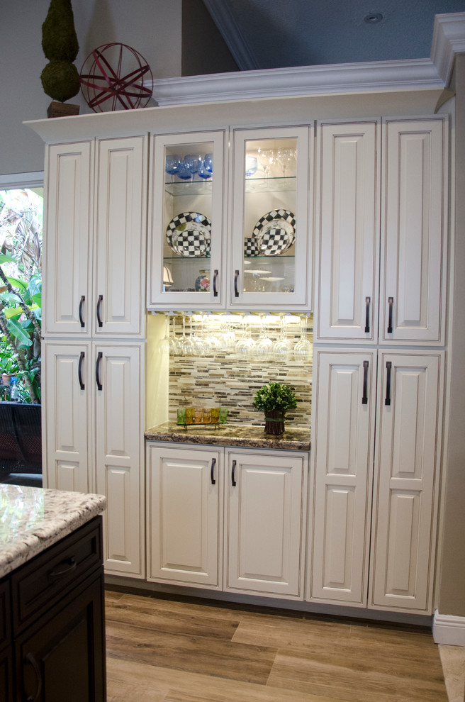 Inspiration for a large transitional l-shaped porcelain tile open concept kitchen remodel in Miami with a farmhouse sink, raised-panel cabinets, white cabinets, granite countertops, multicolored backsplash, mosaic tile backsplash, stainless steel appliances and an island