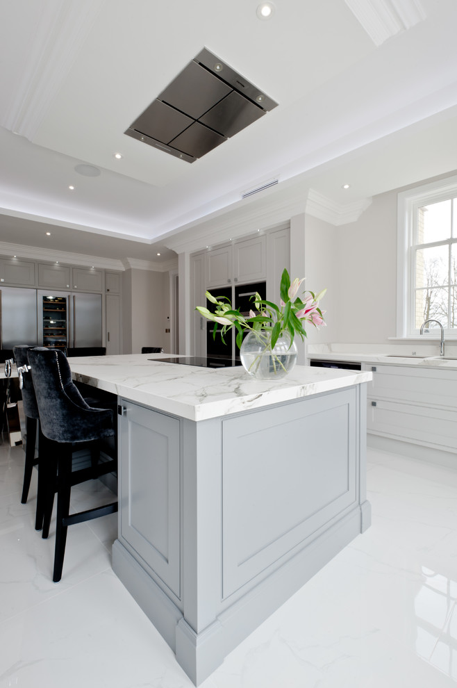 This is an example of a large transitional eat-in kitchen in Kent with an undermount sink, beaded inset cabinets, grey cabinets, solid surface benchtops, panelled appliances, with island and grey floor.