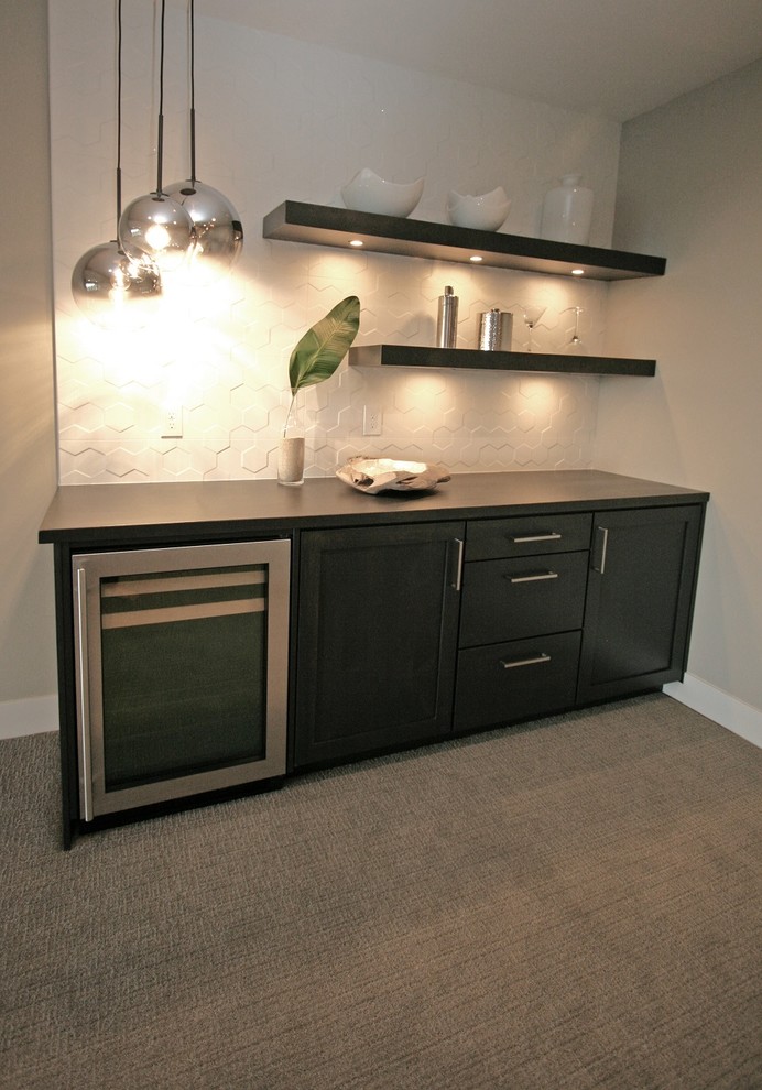 This is an example of a small contemporary single-wall home bar in Seattle with shaker cabinets, black cabinets, wood benchtops, white splashback, porcelain splashback, carpet, grey floor and black benchtop.