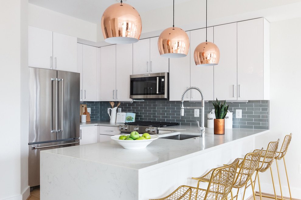 Inspiration for a transitional u-shaped medium tone wood floor and beige floor kitchen remodel with a single-bowl sink, flat-panel cabinets, white cabinets, gray backsplash, glass tile backsplash, stainless steel appliances, a peninsula and white countertops