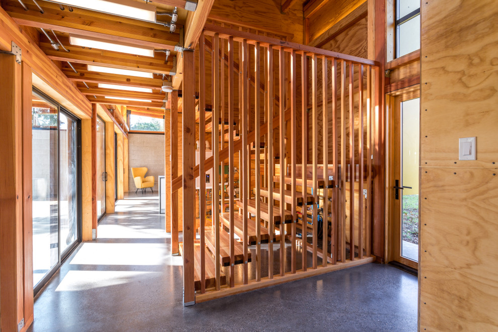 Foto di una grande scala a "U" minimalista con pedata in legno, nessuna alzata, parapetto in legno e pareti in legno