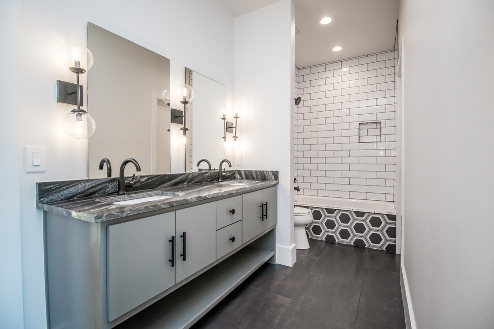 Design ideas for a mid-sized contemporary 3/4 bathroom in Other with flat-panel cabinets, grey cabinets, an alcove tub, a shower/bathtub combo, a two-piece toilet, white tile, subway tile, white walls, an undermount sink, black floor and black benchtops.