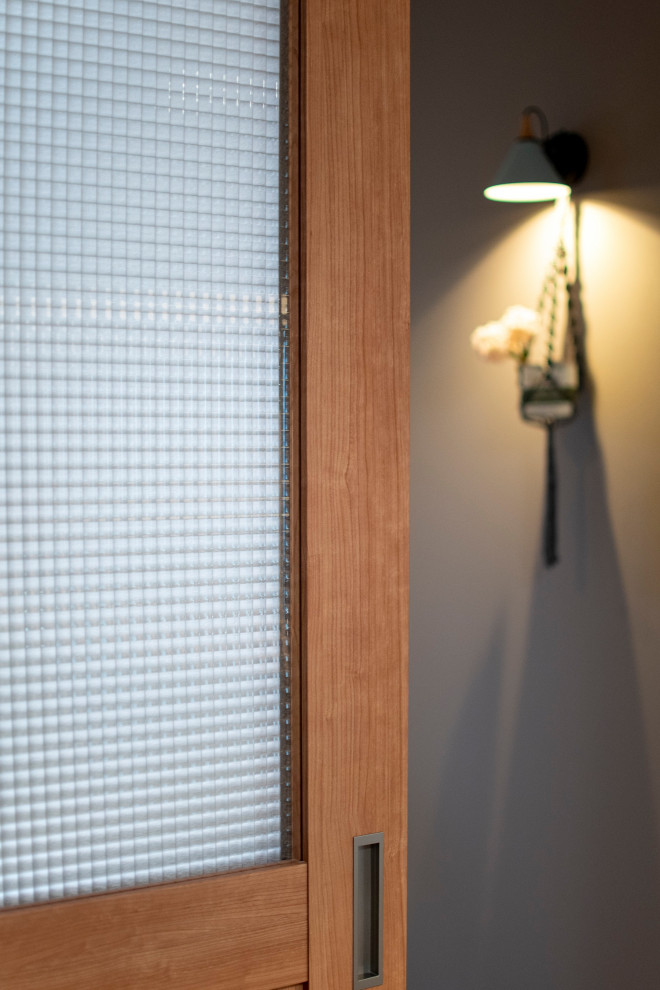 Immagine di un piccolo corridoio moderno con pareti grigie, pavimento in compensato, una porta singola, una porta in legno chiaro, pavimento marrone, soffitto in carta da parati e carta da parati