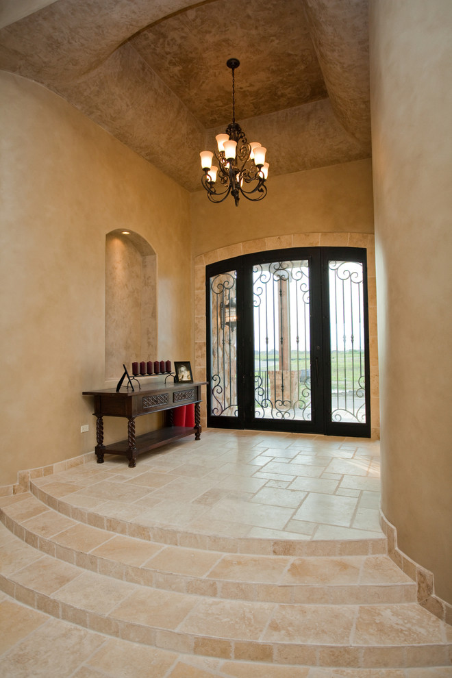 This is an example of a large mediterranean foyer in Chicago with beige walls, limestone floors, a single front door and a metal front door.