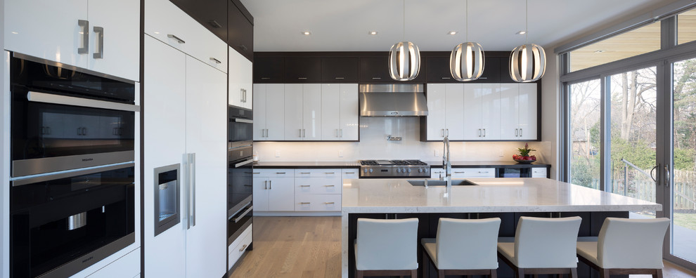 Inspiration for a large modern l-shaped eat-in kitchen in Toronto with a double-bowl sink, flat-panel cabinets, white cabinets, marble benchtops, white splashback, slate splashback, stainless steel appliances, light hardwood floors, with island and yellow floor.
