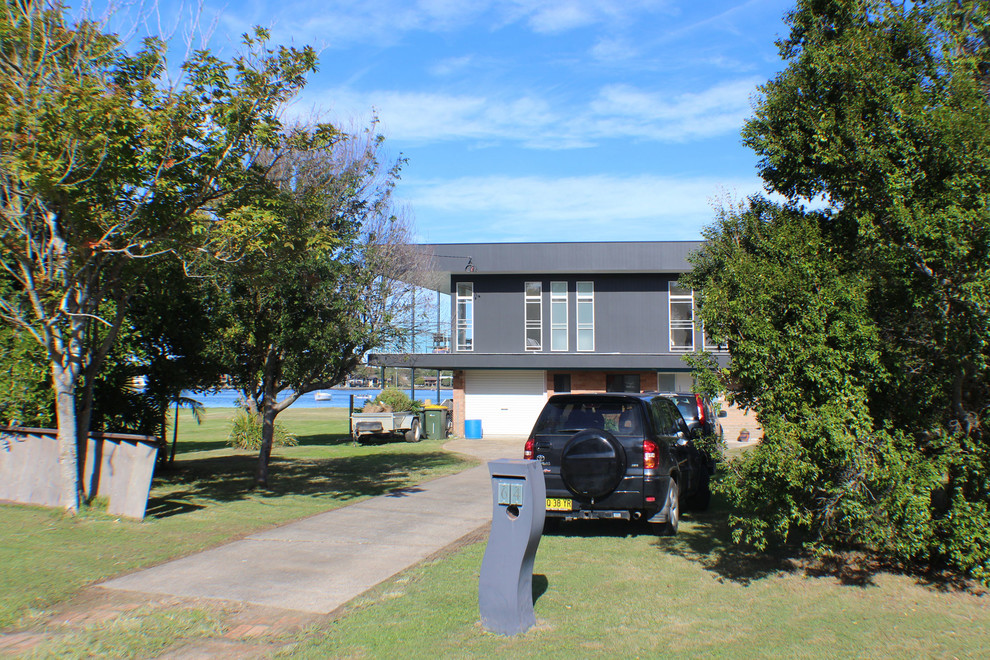 This is an example of a small contemporary two-storey black house exterior in Central Coast with concrete fiberboard siding, a flat roof and a metal roof.