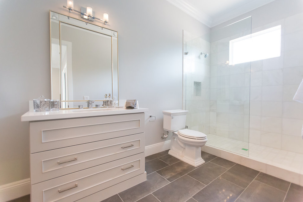 Inspiration for a large transitional 3/4 bathroom in Phoenix with a one-piece toilet, grey walls, an undermount sink, recessed-panel cabinets, white cabinets, grey floor, an alcove shower, gray tile, marble, porcelain floors, marble benchtops and a hinged shower door.