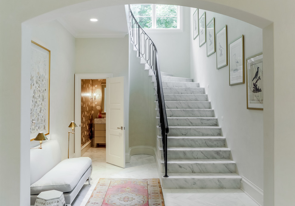 This is an example of a transitional marble curved staircase in Dallas with marble risers and metal railing.