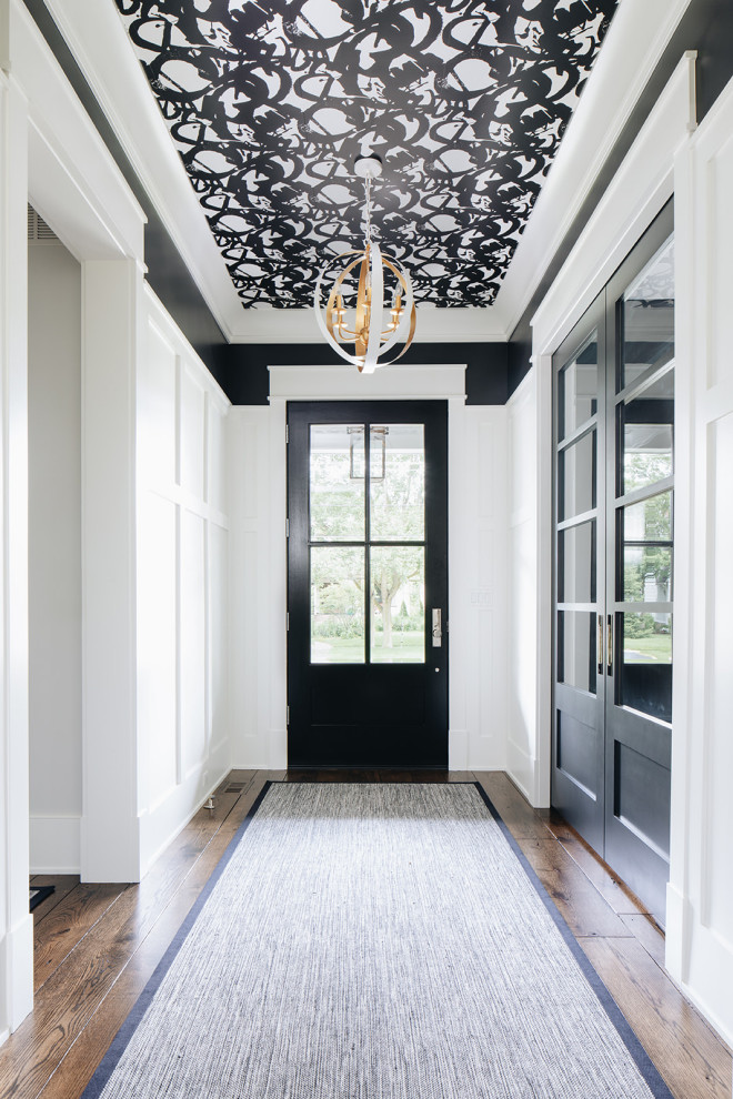 Design ideas for a large transitional foyer in Chicago with black walls, dark hardwood floors, a single front door, a black front door and brown floor.