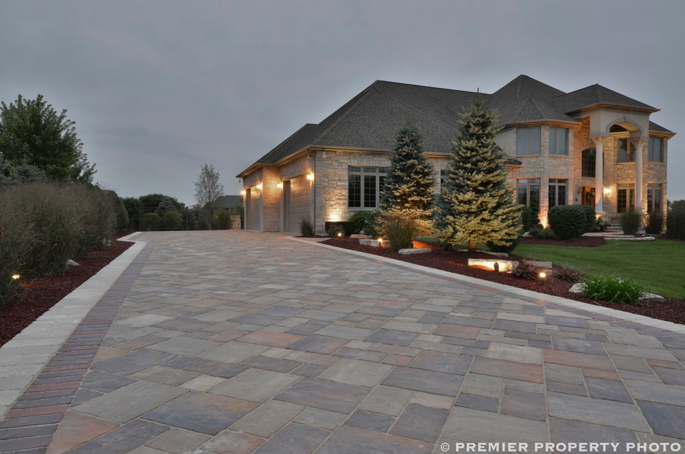 Photo of an expansive contemporary front yard driveway in Chicago with concrete pavers.