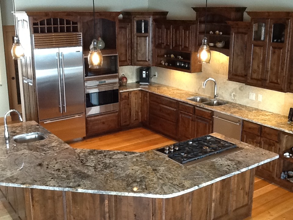 Light wood floor kitchen photo with an undermount sink, granite countertops, stone slab backsplash and an island