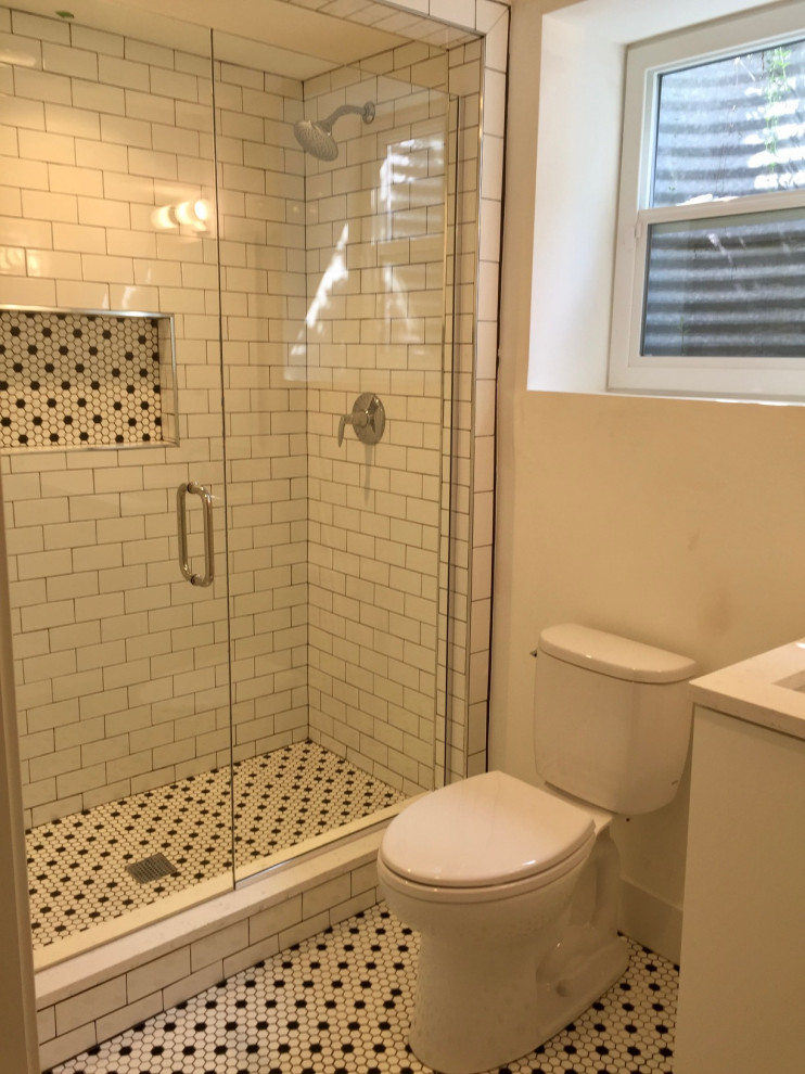デトロイトにあるお手頃価格の小さなモダンスタイルのおしゃれな浴室 (分離型トイレ、白いタイル、サブウェイタイル、白い壁、セラミックタイルの床、開き戸のシャワー、白いキャビネット、珪岩の洗面台) の写真