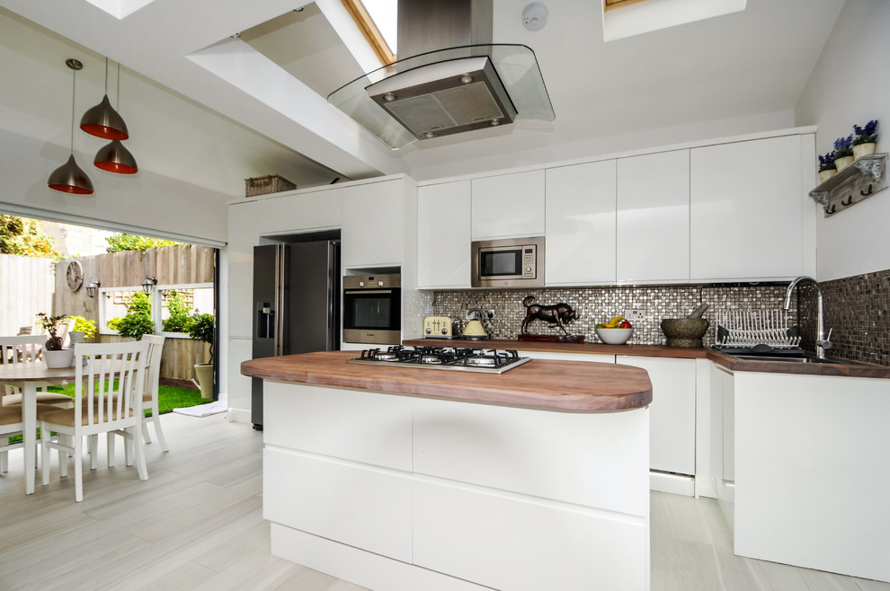 Design ideas for a mid-sized contemporary single-wall open plan kitchen in London with light wood cabinets, zinc benchtops, metallic splashback, mosaic tile splashback, porcelain floors and with island.