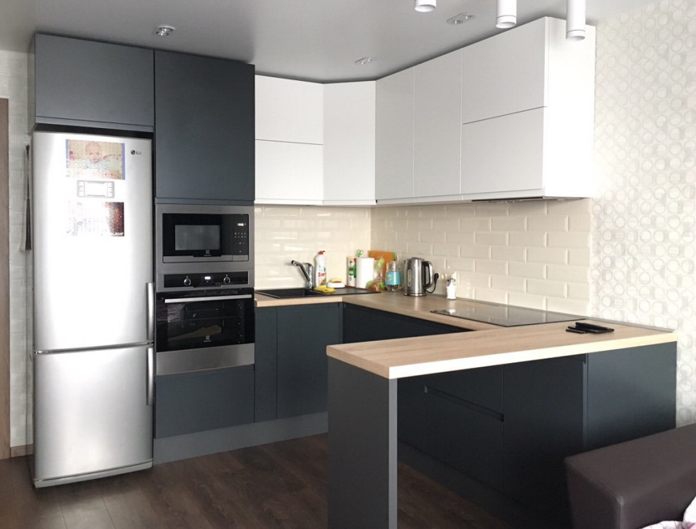 Small modern u-shaped open plan kitchen in Other with a drop-in sink, flat-panel cabinets, grey cabinets, wood benchtops, white splashback, ceramic splashback, stainless steel appliances, laminate floors, a peninsula, brown floor, beige benchtop and coffered.