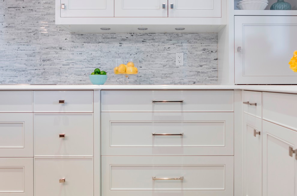 Eat-in kitchen - transitional u-shaped medium tone wood floor eat-in kitchen idea in Toronto with an undermount sink, recessed-panel cabinets, white cabinets, quartz countertops, white backsplash, stone tile backsplash, stainless steel appliances and an island