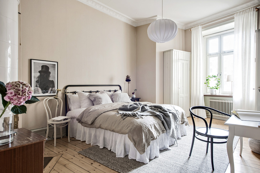 This is an example of a large scandinavian master bedroom in Gothenburg with beige walls, light hardwood floors and no fireplace.