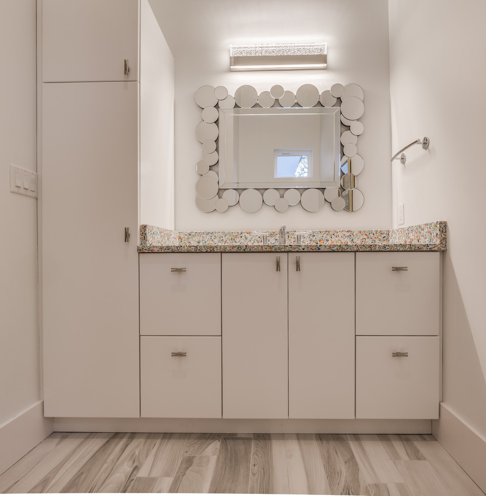 Mid-sized contemporary bathroom in Jacksonville with flat-panel cabinets, grey cabinets, gray tile, ceramic tile, white walls, porcelain floors, an undermount sink, granite benchtops, grey floor and brown benchtops.