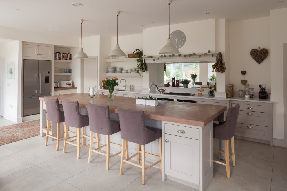 Mid-sized contemporary l-shaped eat-in kitchen in Other with an integrated sink, shaker cabinets, grey cabinets, wood benchtops, glass sheet splashback, stainless steel appliances, ceramic floors, with island, beige floor and beige benchtop.