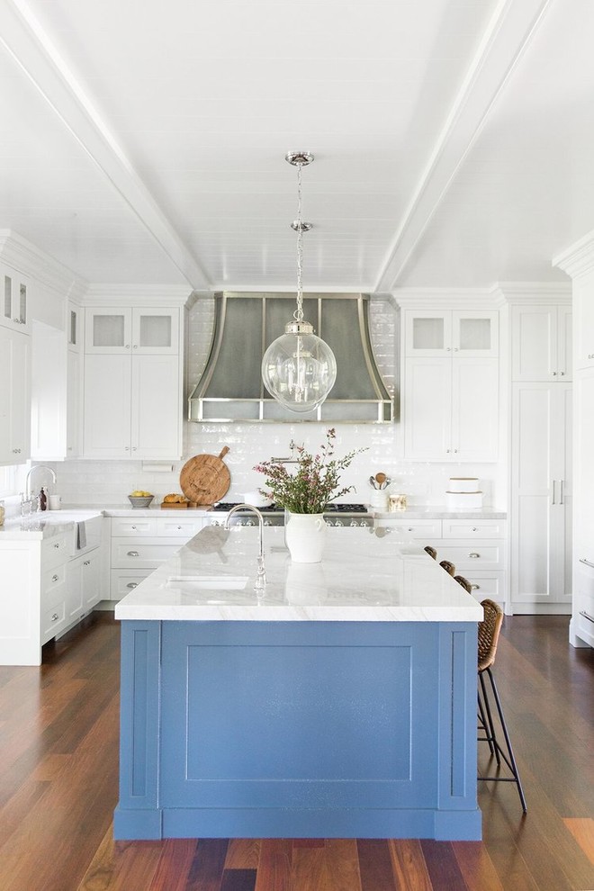 This is an example of a large traditional l-shaped kitchen in Salt Lake City with a farmhouse sink, shaker cabinets, blue cabinets, white splashback, subway tile splashback, stainless steel appliances, dark hardwood floors, with island and white benchtop.