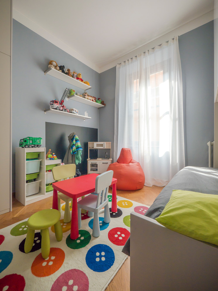This is an example of a large contemporary kids' bedroom for kids 4-10 years old and boys in Milan with blue walls and light hardwood floors.