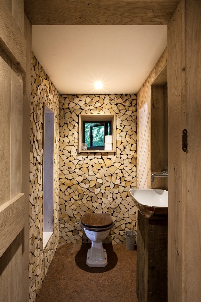 Inspiration for a mid-sized country powder room in Dorset with a one-piece toilet, a vessel sink, brown floor and dark wood cabinets.