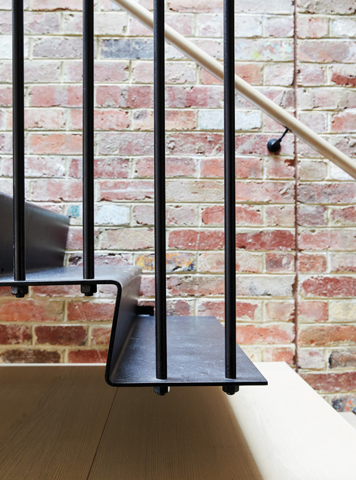 Ejemplo de escalera en L urbana de tamaño medio con escalones de metal, contrahuellas de metal, barandilla de madera y ladrillo