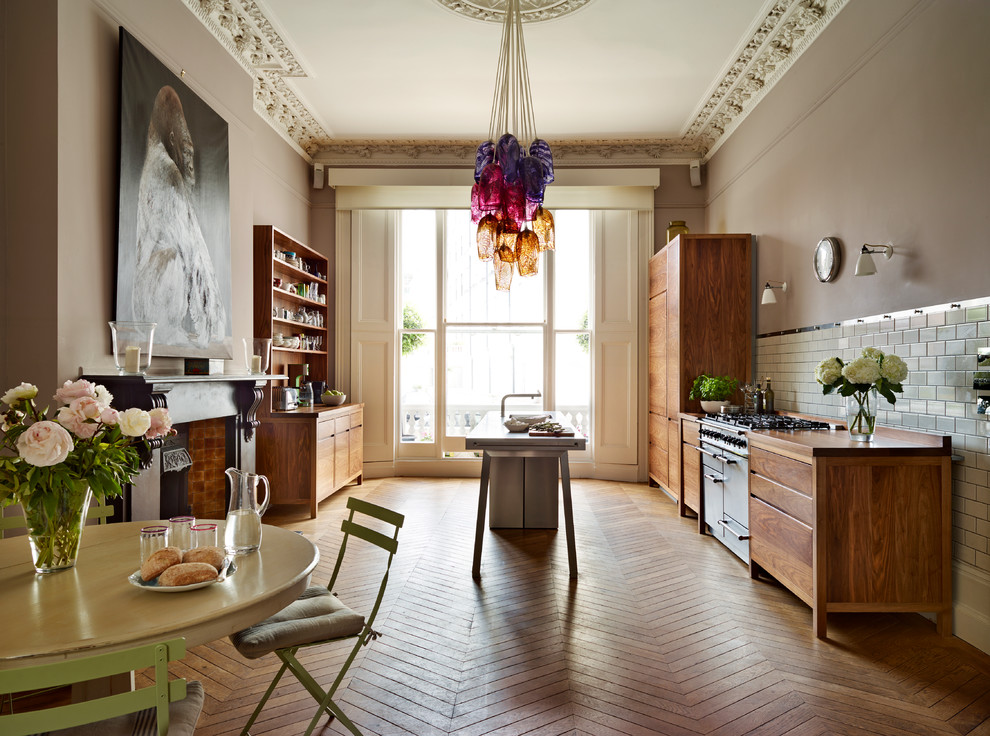 Inspiration for an eclectic galley eat-in kitchen in Other with flat-panel cabinets, medium wood cabinets, wood benchtops, white splashback, subway tile splashback, stainless steel appliances, medium hardwood floors, with island and brown floor.