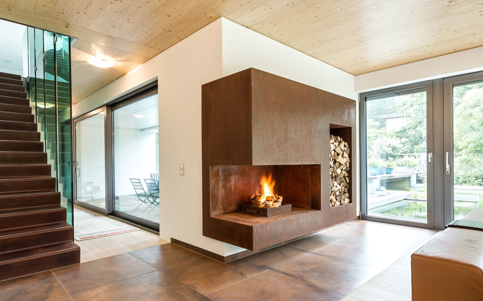 This is an example of a large contemporary open concept living room in Berlin with white walls and a metal fireplace surround.