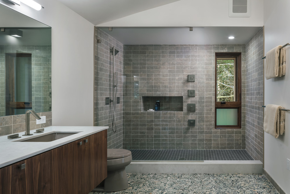 Contemporary master bathroom in Portland with flat-panel cabinets, medium wood cabinets, an open shower, gray tile, white walls, pebble tile floors, an undermount sink, multi-coloured floor, an open shower and white benchtops.