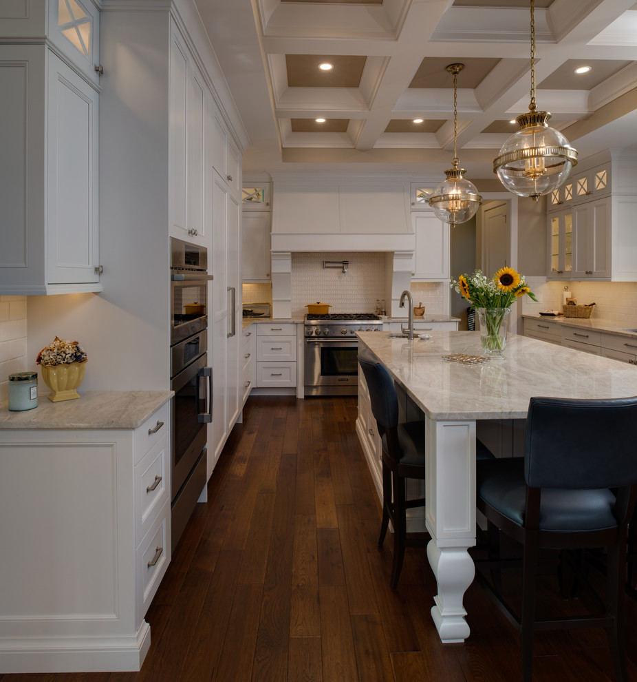 Large transitional u-shaped eat-in kitchen in Detroit with an undermount sink, beaded inset cabinets, white cabinets, quartzite benchtops, white splashback, porcelain splashback, panelled appliances, medium hardwood floors, with island, brown floor and beige benchtop.
