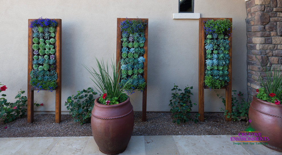 Expansive modern patio in Phoenix with a vertical garden, brick pavers and a roof extension.