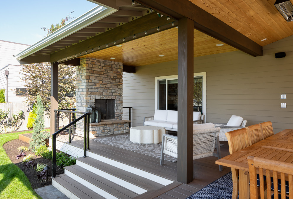 Cette photo montre une grande terrasse arrière et au rez-de-chaussée tendance avec une cuisine d'été, une extension de toiture et un garde-corps en câble.
