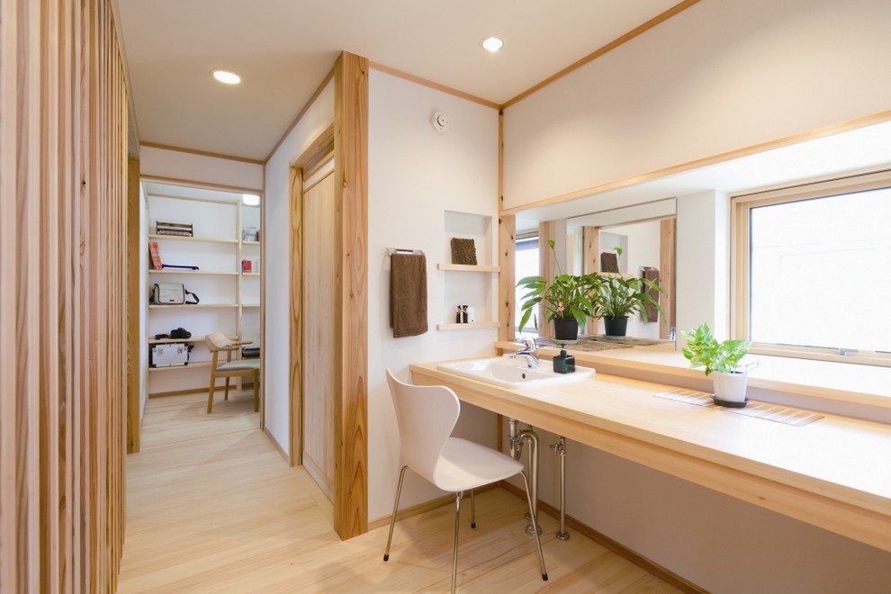 This is an example of an asian bathroom in Other with white walls, light hardwood floors, a drop-in sink, wood benchtops, beige floor and beige benchtops.