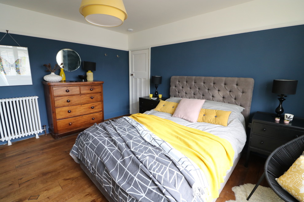 Mid-sized eclectic master bedroom in Cambridgeshire with blue walls, dark hardwood floors, a standard fireplace and a tile fireplace surround.